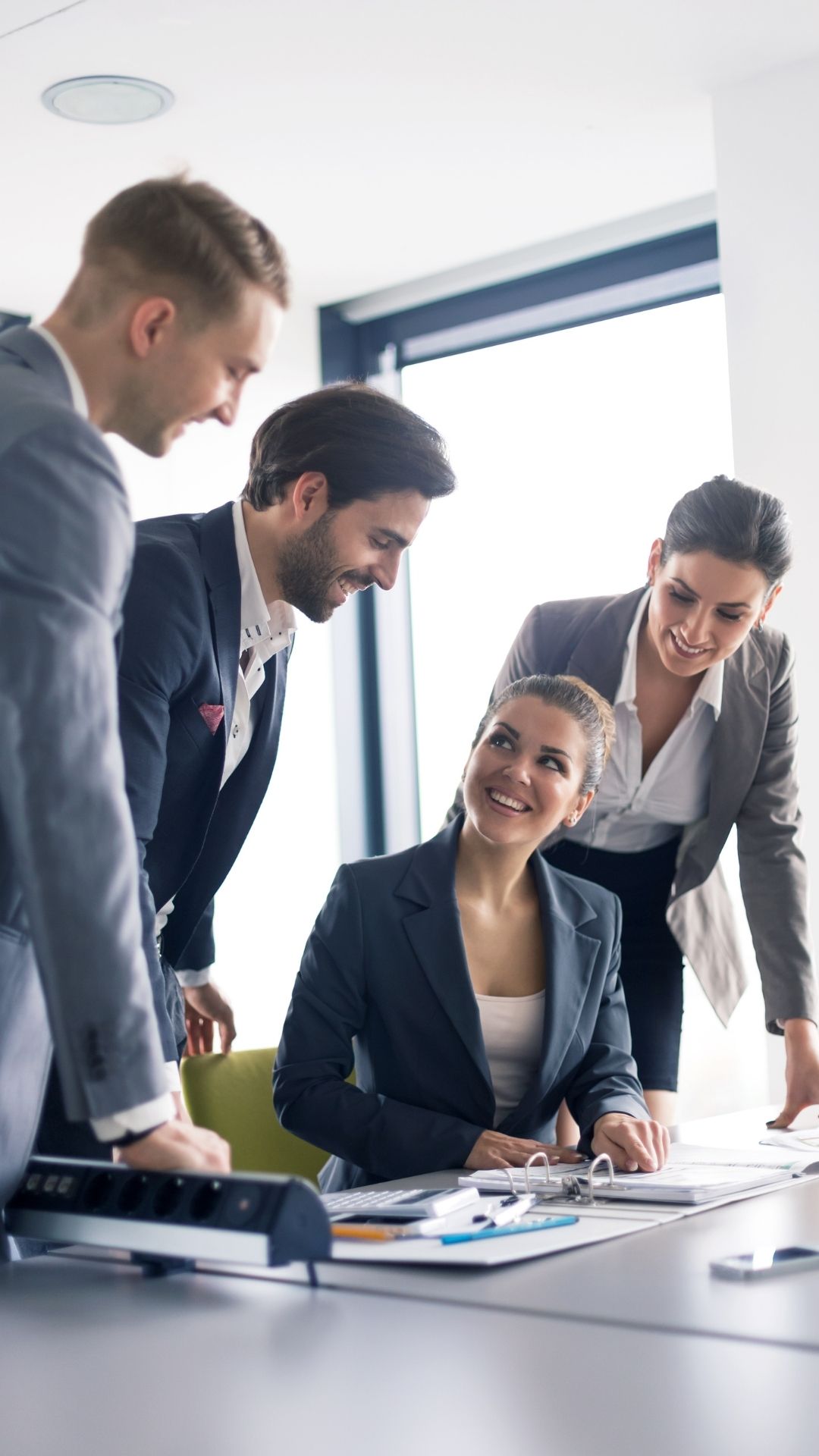 Three individuals are dressed in corporate attire and smiling