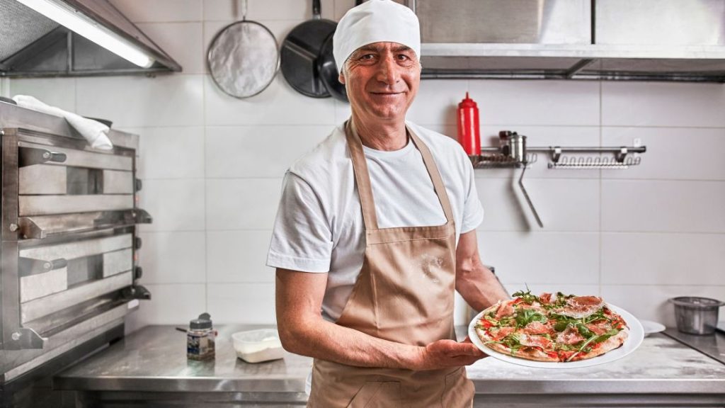 Baker Showing newly cooked Pizza