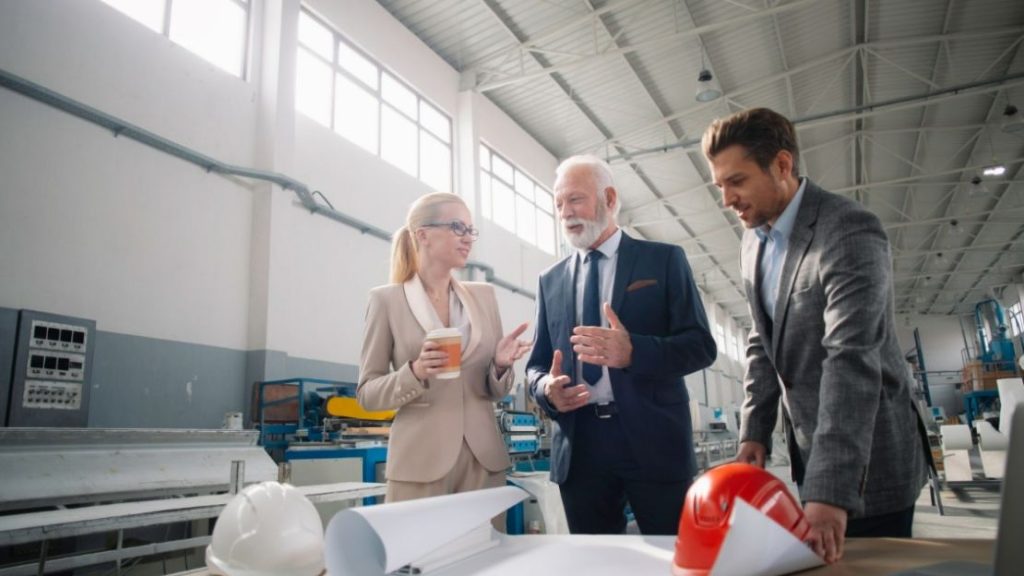 Three people are having a discussion about their manufacturing plans